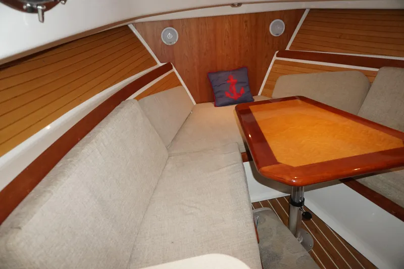 Halcyon Yacht Photos Pics 2006 Back Cove 29 interior with wooden table, beige seating, and nautical-themed pillow.