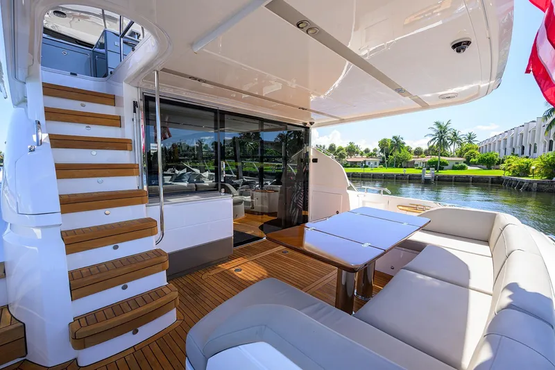 Miss Amy Yacht Photos Pics Luxurious 2020 Princess F70 yacht deck with seating, table, and staircase, overlooking serene waterfront.