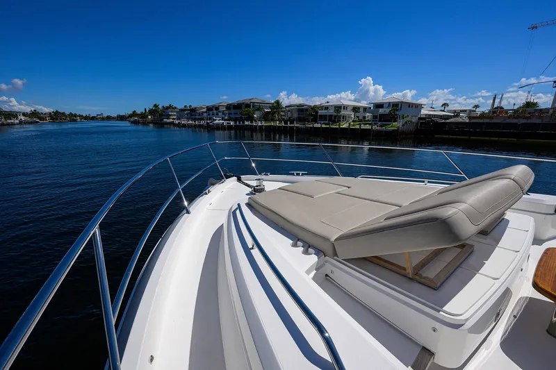 Miss Amy Yacht Photos Pics Luxury 2020 Princess F70 yacht with sunbed on deck, cruising along a scenic waterfront.