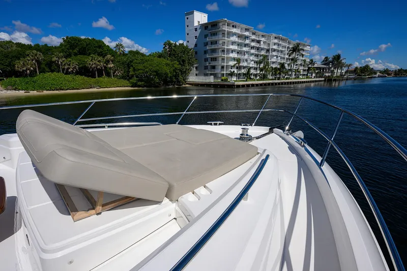 Miss Amy Yacht Photos Pics Luxury Princess F70 yacht deck with sunbed, overlooking waterfront buildings and lush greenery.