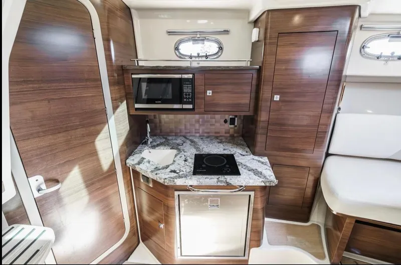  Yacht Photos Pics 2019 Boston Whaler 345 Conquest interior kitchen with microwave, stove, and wood cabinetry.