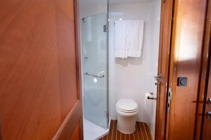 Ok'd By Dad Yacht Photos Pics Luxurious bathroom in 2001 Mikelson 61 Yachtfisher with glass shower and wooden accents.