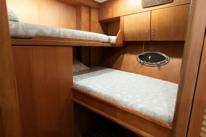 Ok'd By Dad Yacht Photos Pics Interior cabin of 2001 Mikelson 61 Yachtfisher with wooden bunk beds and porthole.