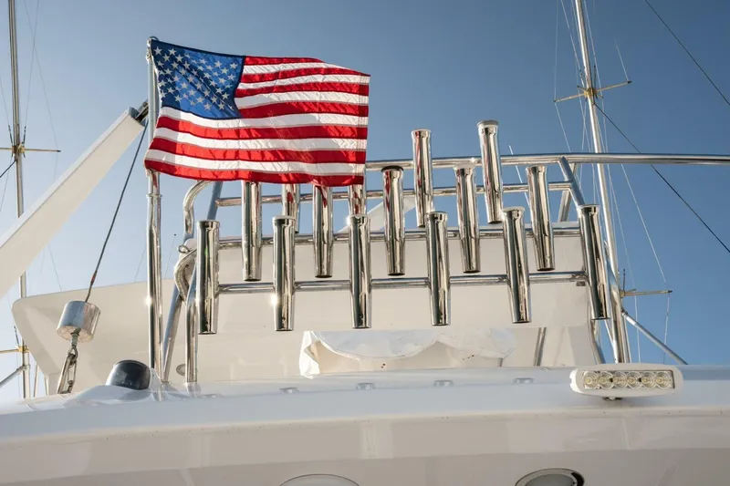 Ok'd By Dad Yacht Photos Pics American flag on 2001 Mikelson 61 Yachtfisher, with clear blue sky background.