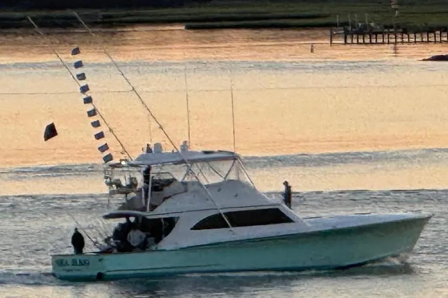 Custom Carolina Blackwell 2007 boat on calm water at sunset with fishing flags.