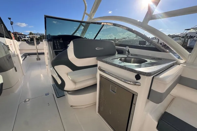  Yacht Photos Pics 2021 Robalo R317 Dual Console boat interior with seating and kitchenette under sunny sky.