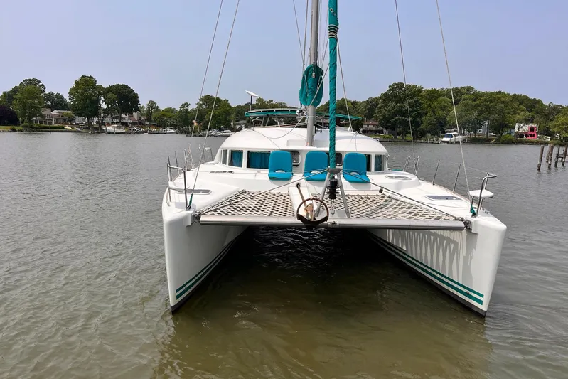 Wayward Sun Yacht Photos Pics 2000 Lagoon 380 catamaran on calm water, featuring a spacious deck and vibrant accents.