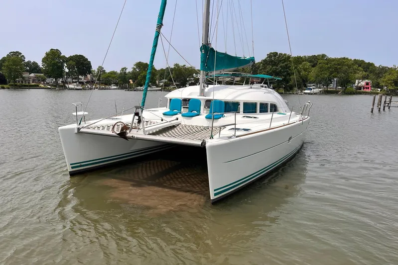 Wayward Sun Yacht Photos Pics 2000 Lagoon 380 catamaran docked on calm water, surrounded by trees.