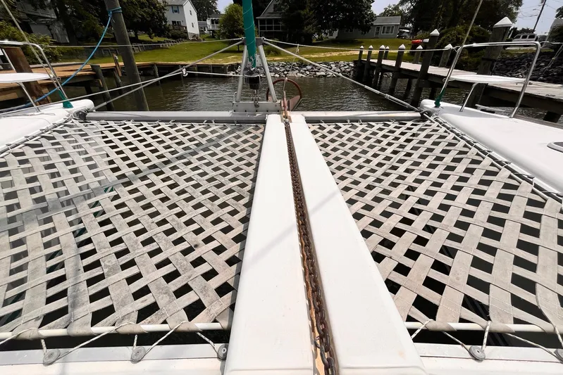 Wayward Sun Yacht Photos Pics Catamaran Lagoon 380 (2000) with netting, docked in a serene marina setting.