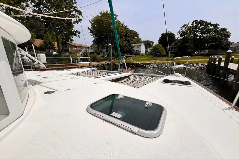 Wayward Sun Yacht Photos Pics Lagoon 380 catamaran docked, showcasing deck and hatch, surrounded by trees and houses.