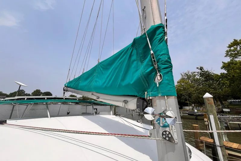 Wayward Sun Yacht Photos Pics Lagoon 380 sailboat from 2000 with teal sail cover, docked near trees.