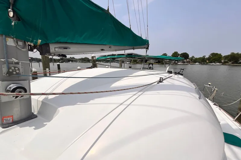 Wayward Sun Yacht Photos Pics Lagoon 380 catamaran, 2000 model, docked with green sail cover, calm waters in background.