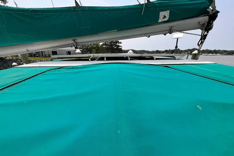 Wayward Sun Yacht Photos Pics Lagoon 380 catamaran (2000) with teal sail cover, docked by a serene waterfront.