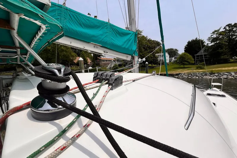 Wayward Sun Yacht Photos Pics Lagoon 380 sailboat deck with ropes and winch, docked near a grassy shoreline.