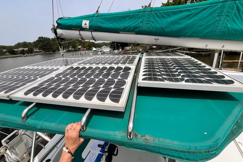 Wayward Sun Yacht Photos Pics Solar panels on a 2000 Lagoon 380 catamaran with green canopy, docked by the water.