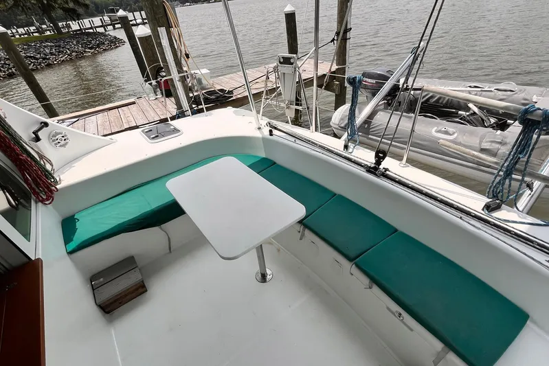 Wayward Sun Yacht Photos Pics Lagoon 380 catamaran cockpit with green seating and table, docked by the water.