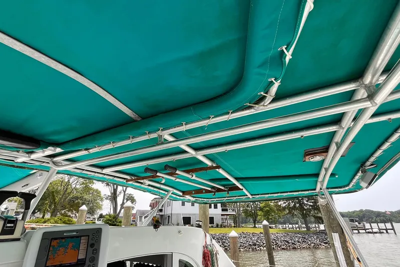 Wayward Sun Yacht Photos Pics Lagoon 380 catamaran cockpit with teal canopy, showcasing navigation equipment, docked by waterfront homes.