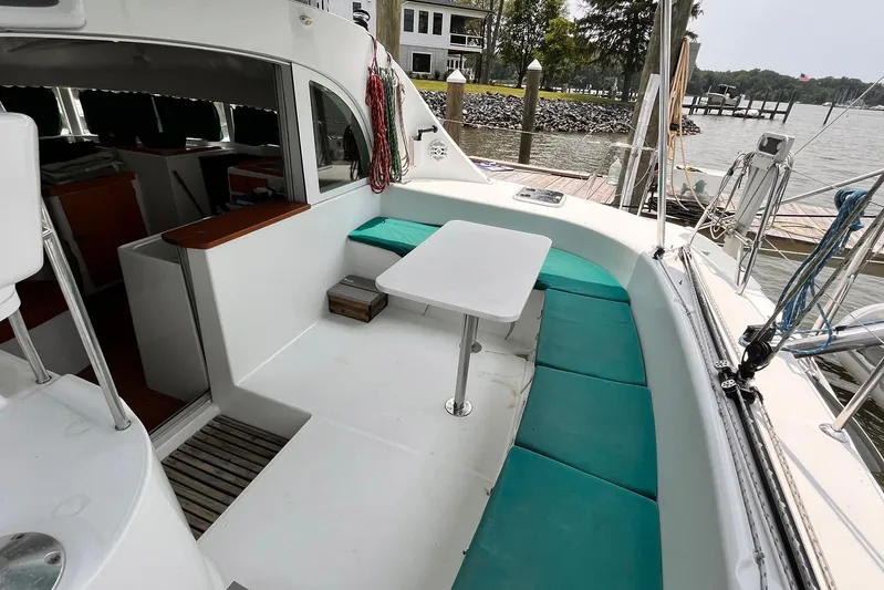 Wayward Sun Yacht Photos Pics Lagoon 380 catamaran cockpit with teal seating and table, docked by the water.