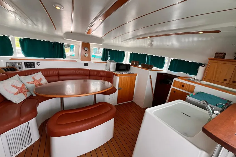 Wayward Sun Yacht Photos Pics Interior of 2000 Lagoon 380 catamaran with cozy seating, table, and kitchenette.