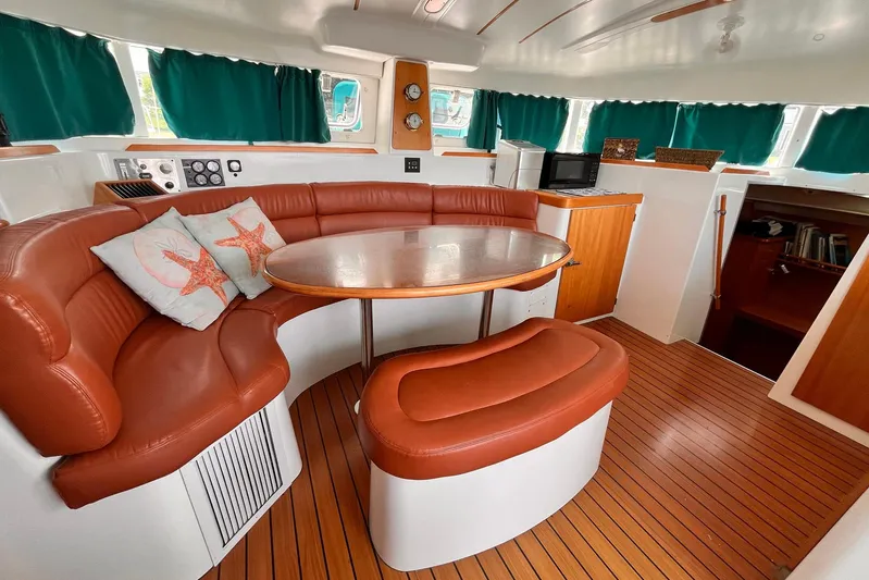 Wayward Sun Yacht Photos Pics Interior of 2000 Lagoon 380 catamaran with leather seating, wooden flooring, and starfish-themed pillows.