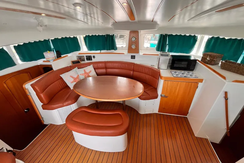 Wayward Sun Yacht Photos Pics Interior of 2000 Lagoon 380 catamaran with cozy seating, table, and kitchenette.