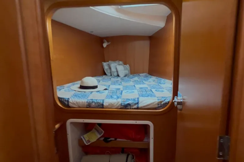 Wayward Sun Yacht Photos Pics Cozy cabin interior of 2000 Lagoon 380 catamaran with bed and hat on quilt.