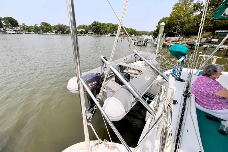 Wayward Sun Yacht Photos Pics Lagoon 380 catamaran with dinghy and Yamaha motor, docked by a serene waterfront.