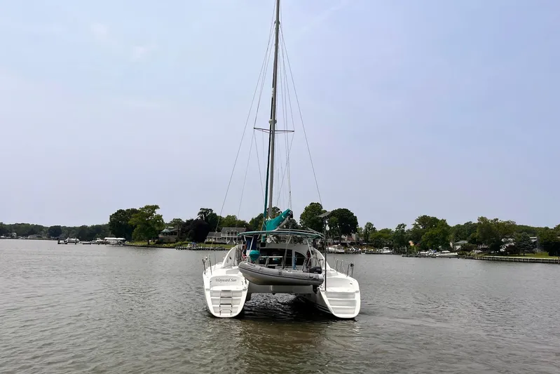 Wayward Sun Yacht Photos Pics Lagoon 380 catamaran from 2000 on a calm river with lush green shoreline.
