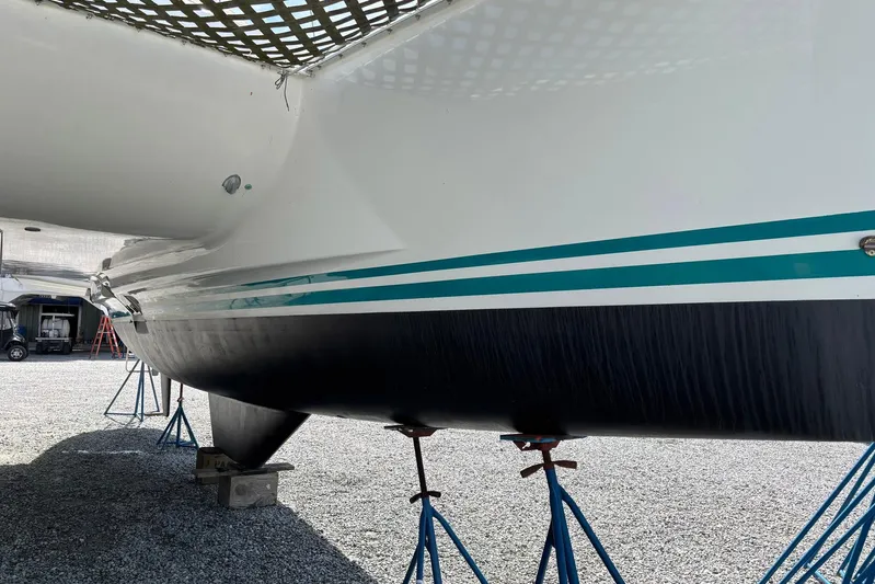 Wayward Sun Yacht Photos Pics Lagoon 380 catamaran from 2000 on stands, showcasing hull and netting.