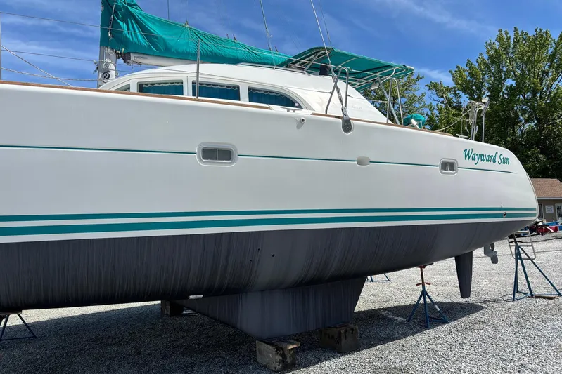 Wayward Sun Yacht Photos Pics Lagoon 380 catamaran from 2000 on dry dock, named "Wayward Sun," with green accents.