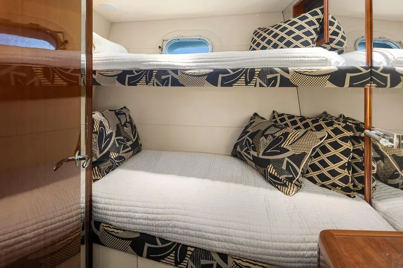 Bellissimo Yacht Photos Pics Cozy bunk beds in 2001 Hatteras 63 Cockpit Motor Yacht cabin, featuring patterned pillows.