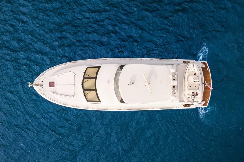 Bellissimo Yacht Photos Pics Aerial view of 2001 Hatteras 63 Cockpit Motor Yacht on blue ocean water.