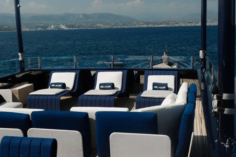 Blade II Yacht Photos Pics Luxurious yacht deck with blue and white seating, overlooking serene ocean and distant coastline.