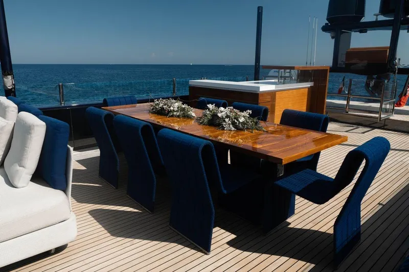 Blade II Yacht Photos Pics Luxurious yacht deck with elegant dining setup, featuring blue chairs and ocean view. MMGI BLADE II, 2009.