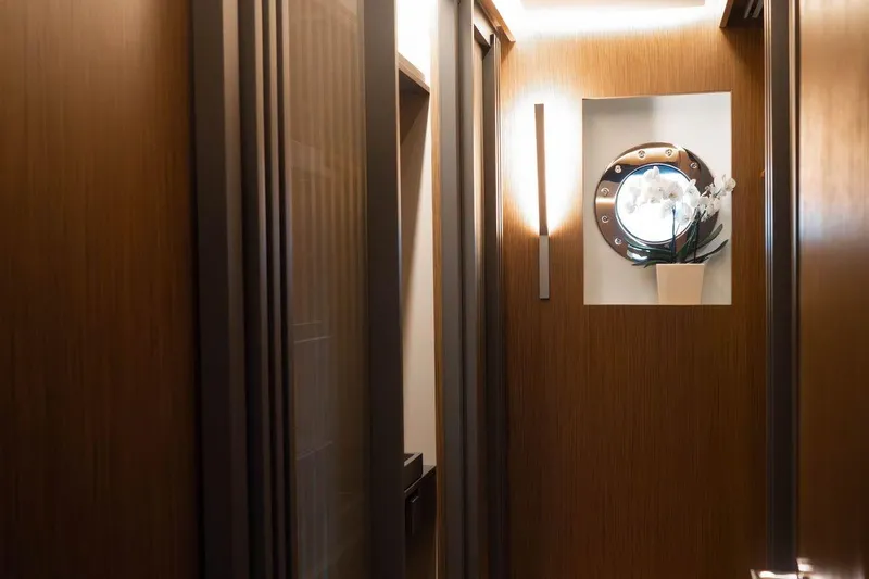 Blade II Yacht Photos Pics Narrow hallway with wooden walls, porthole window, and decorative orchid on MMGI BLADE II yacht.
