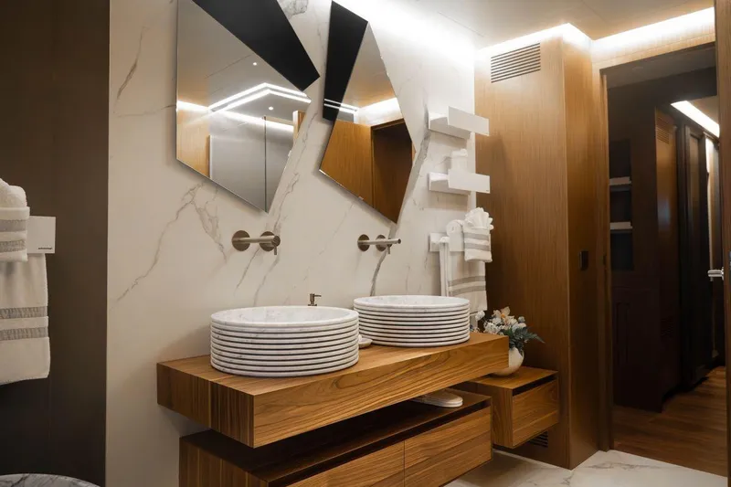 Blade II Yacht Photos Pics Luxurious bathroom with dual vessel sinks, wooden vanity, and modern mirrors on marble wall.