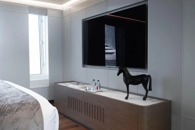Blade II Yacht Photos Pics Modern bedroom with large TV, wooden cabinet, and horse sculpture on MMGI BLADE II yacht.