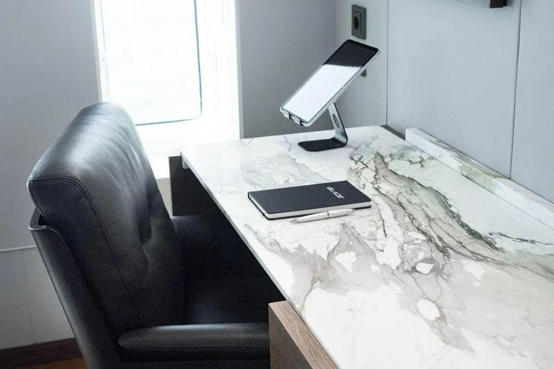 Blade II Yacht Photos Pics Luxurious marble desk with leather chair, tablet stand, and notebook in a modern setting.