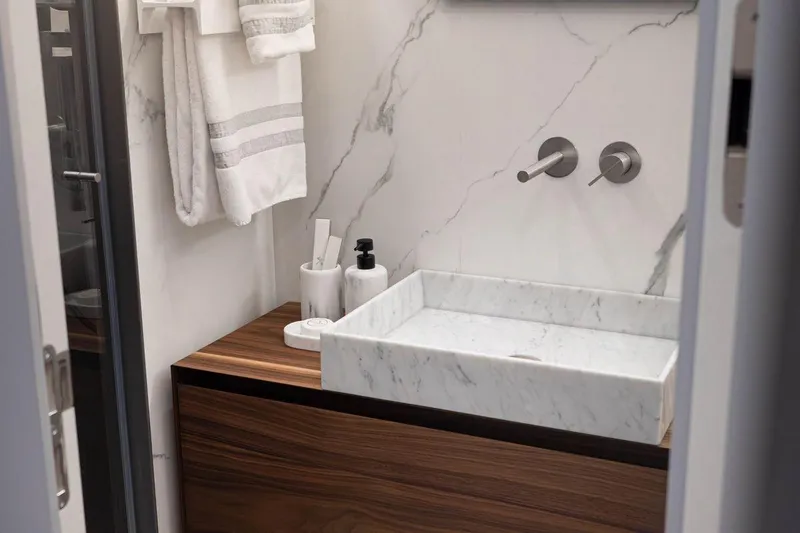 Blade II Yacht Photos Pics Modern bathroom with marble sink, wooden vanity, and wall-mounted faucets in a sleek design.