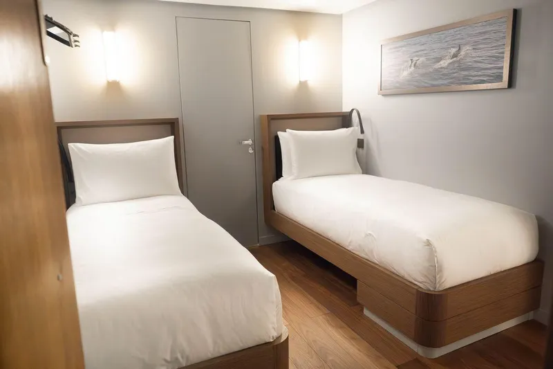 Blade II Yacht Photos Pics Modern hotel room with two single beds, wooden flooring, and soft lighting.