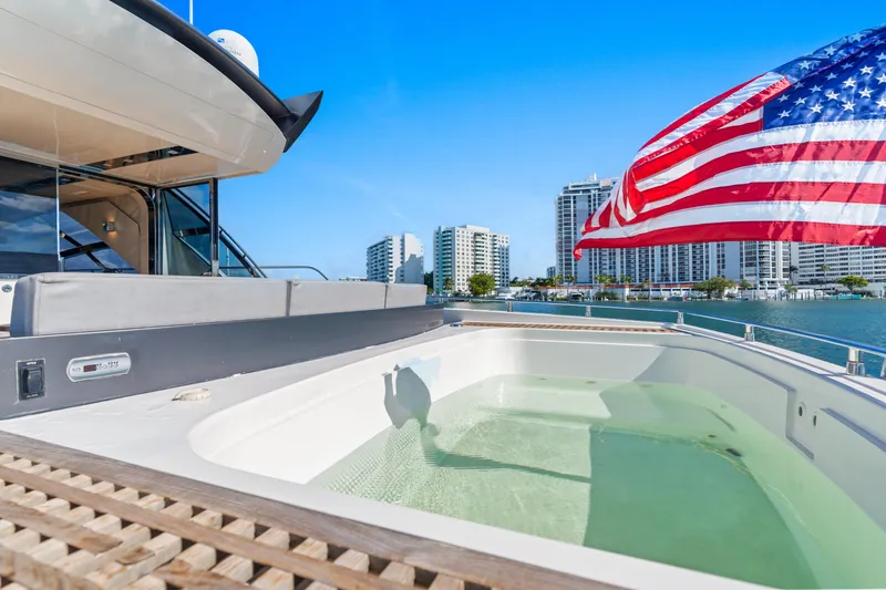 Bikinis Optional Yacht Photos Pics Luxurious 2012 Cheoy Lee 76 Alpha yacht with jacuzzi and American flag, city skyline in background.