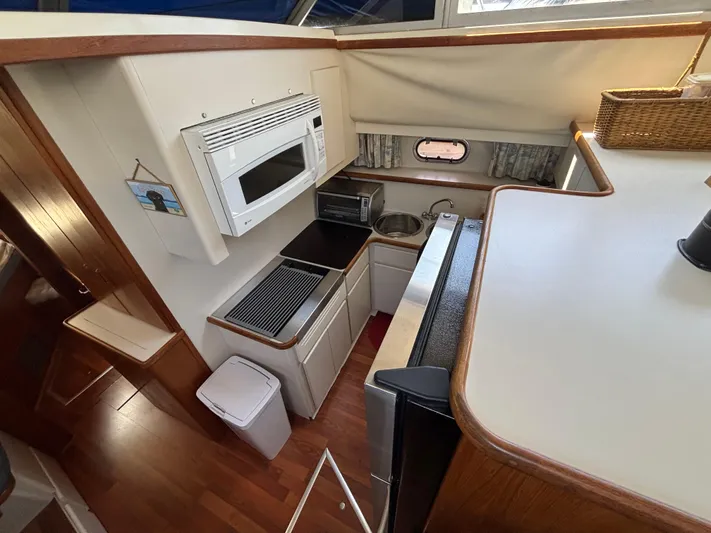  Yacht Photos Pics 1993 Carver 440 Aft Cabin Motor Yacht kitchen with microwave, sink, and wooden cabinetry.