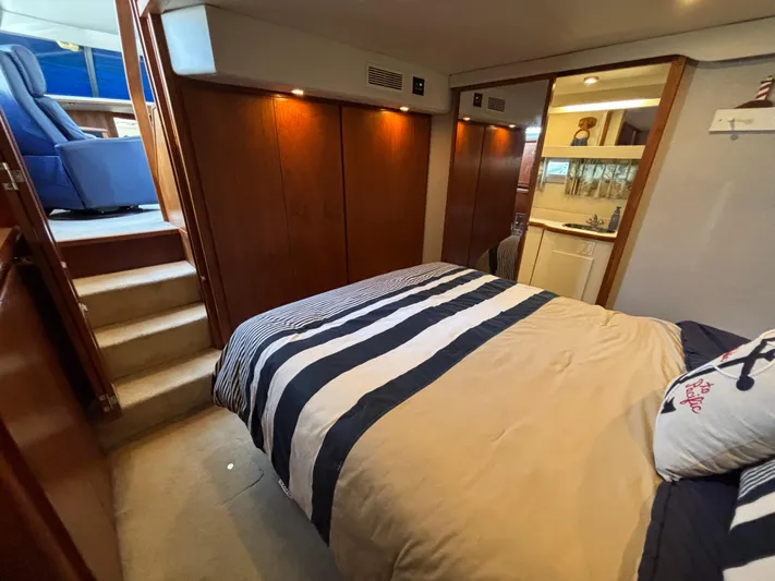  Yacht Photos Pics 1993 Carver 440 Aft Cabin Motor Yacht bedroom with striped bedding and wooden cabinetry.