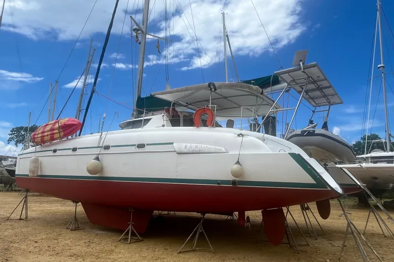 Nikita 1 Yacht Photos Pics 2004 Fountaine Pajot Bahia 46 catamaran on land, with red hull and blue sky background.
