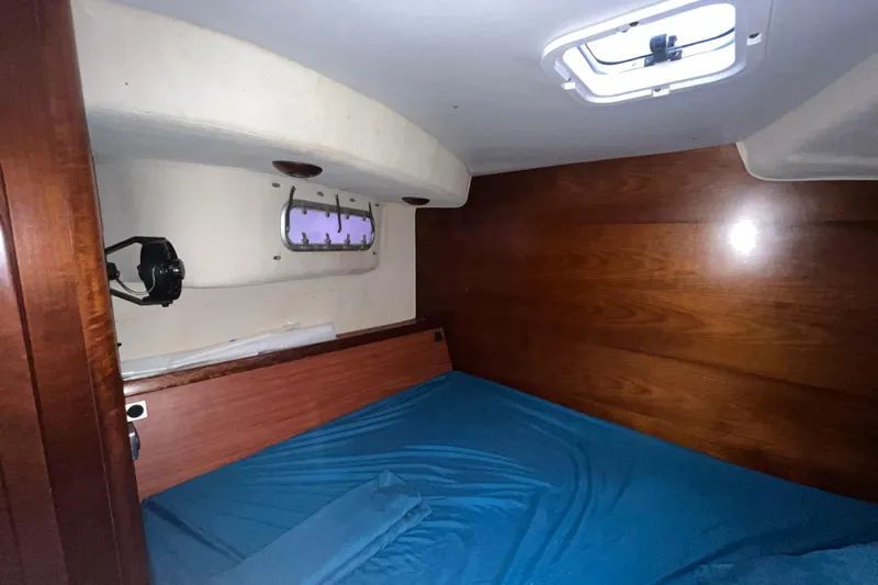 Nikita 1 Yacht Photos Pics Interior cabin of 2004 Fountaine Pajot Bahia 46 catamaran with wooden paneling and blue bedding.