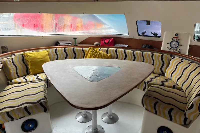 Nikita 1 Yacht Photos Pics Interior of 2004 Fountaine Pajot Bahia 46 catamaran with striped seating and triangular table.