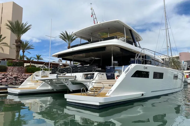 Sona 1 Yacht Photos Pics 2019 Lagoon 630 MY yacht docked in a marina, surrounded by palm trees and clear skies.