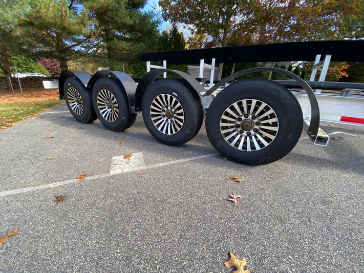  Yacht Photos Pics 2023 Invincible 46 Catamaran Plus Quad Axle Trailer with sleek wheels in a parking lot.