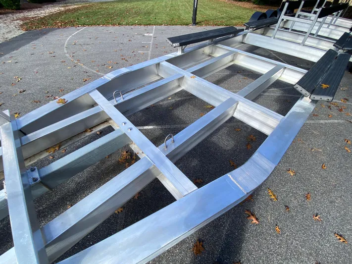  Yacht Photos Pics 2023 Invincible 46 Catamaran Plus Quad Axle Trailer on pavement, showcasing sturdy metal frame.