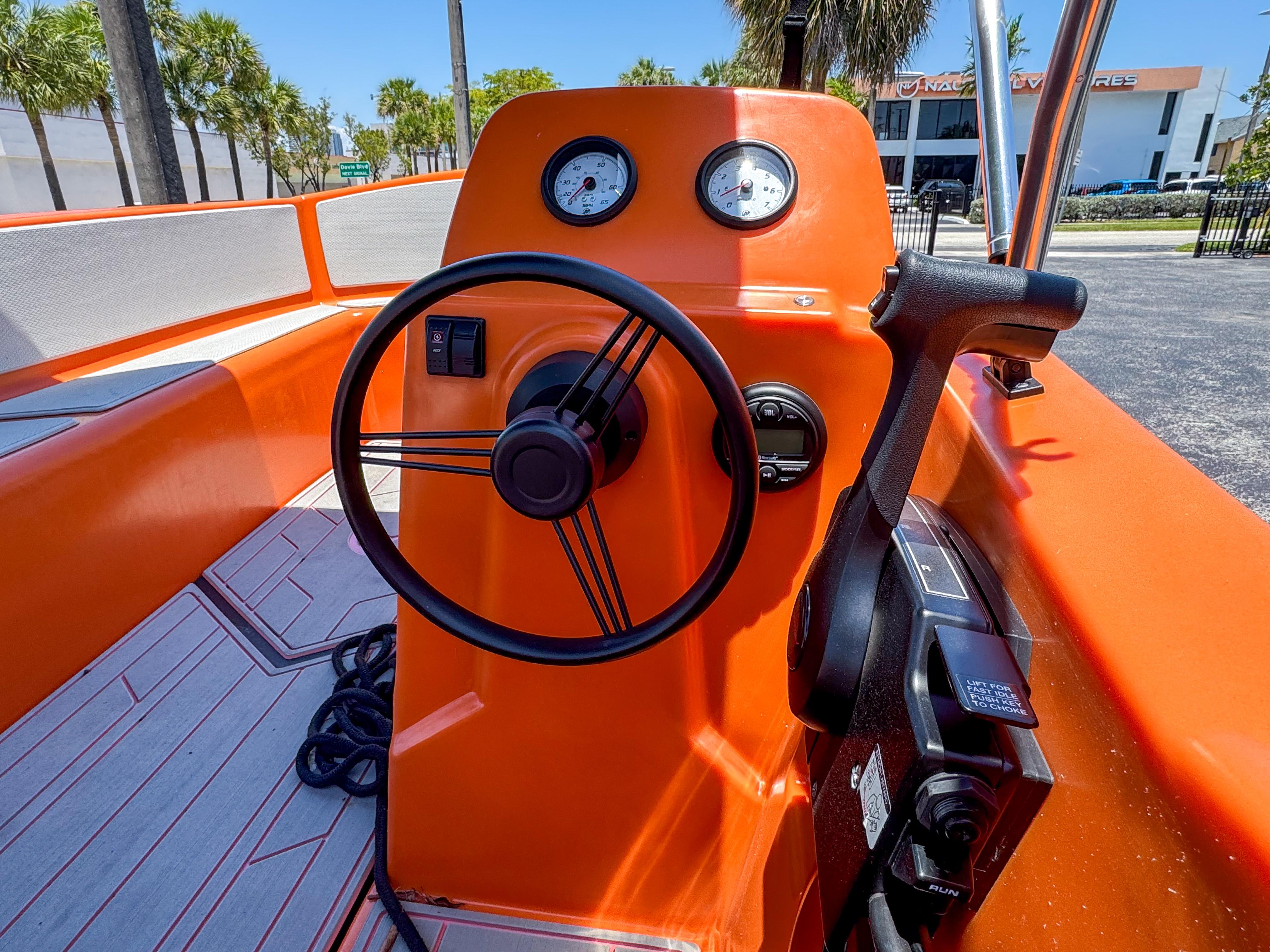 2024 Vision Marine Technologies Phantom boat cockpit with orange dashboard and steering wheel.